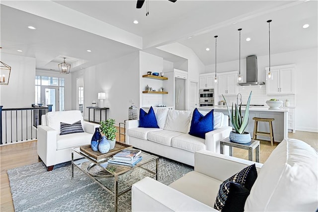 living room featuring ceiling fan with notable chandelier and light wood-type flooring