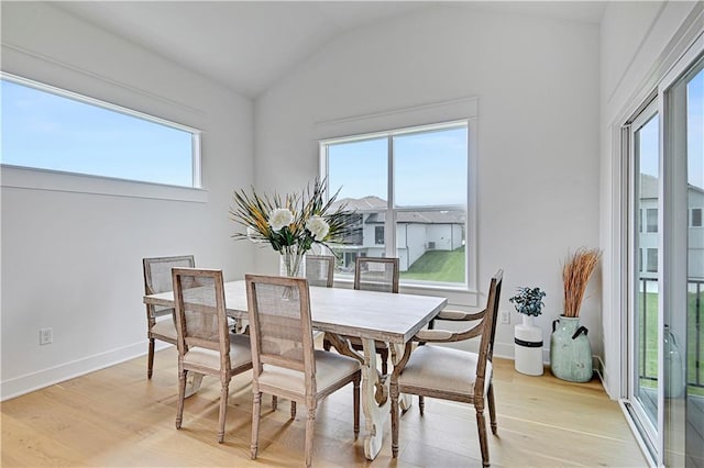 dining room featuring light wood-type flooring and vaulted ceiling