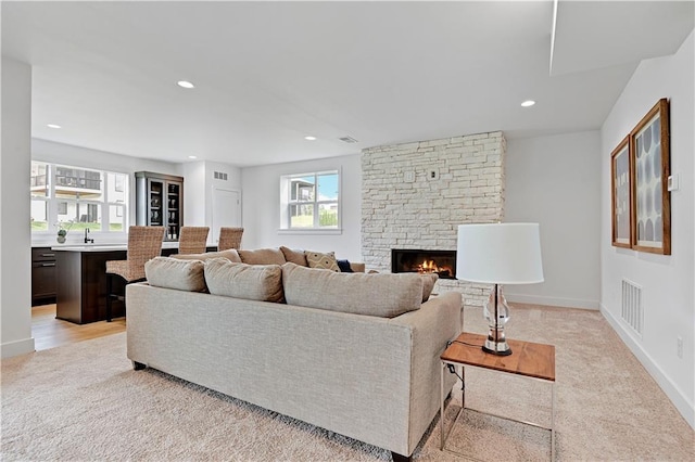 living room featuring light colored carpet and a stone fireplace