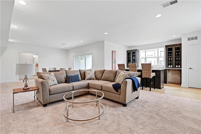 living room featuring light colored carpet and bar