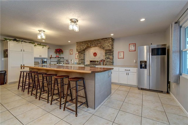 kitchen with a breakfast bar, stainless steel appliances, white cabinetry, and butcher block counters