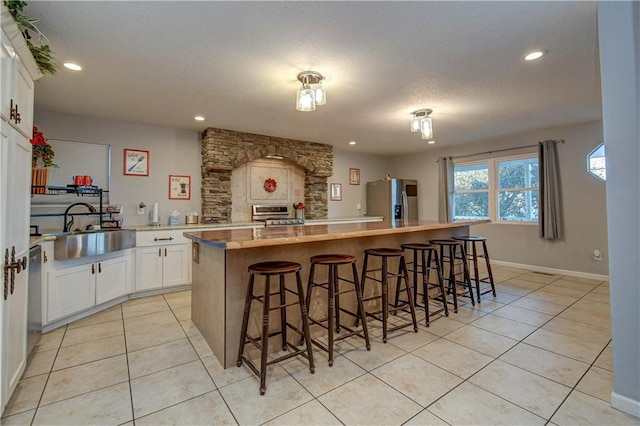 kitchen featuring a kitchen breakfast bar, stainless steel appliances, a kitchen island, sink, and white cabinetry