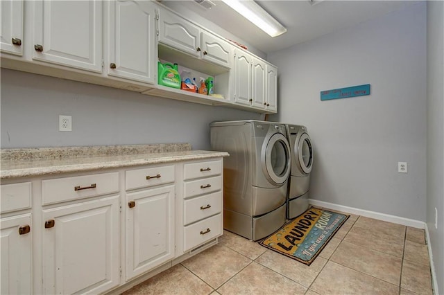 laundry area featuring washer and dryer, light tile patterned flooring, and cabinets