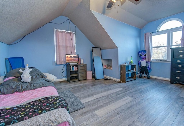 bedroom featuring a textured ceiling, ceiling fan, lofted ceiling, and light wood-type flooring