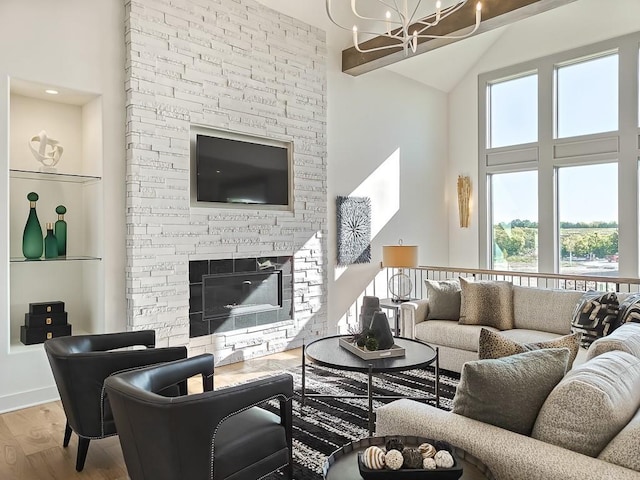 living room with wood-type flooring, a stone fireplace, and a notable chandelier