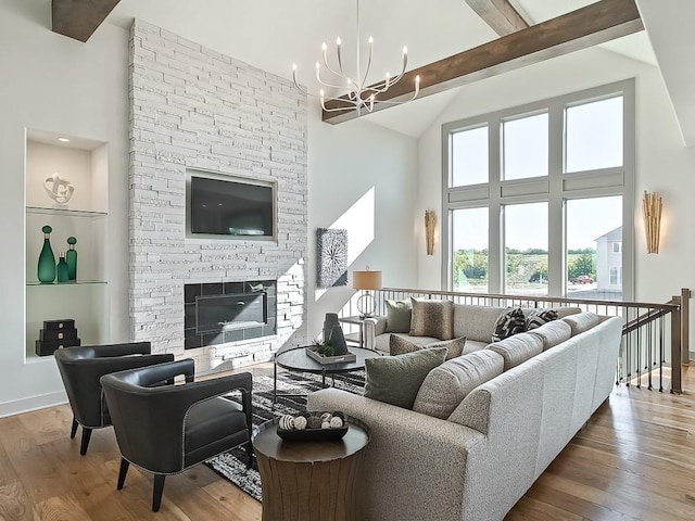 living room with a fireplace, vaulted ceiling with beams, hardwood / wood-style flooring, and a chandelier