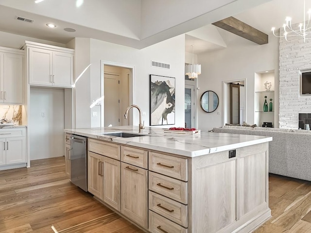 kitchen with sink, pendant lighting, beam ceiling, a center island with sink, and dishwasher