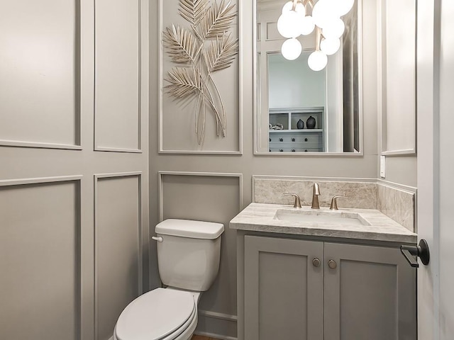 bathroom with vanity, a notable chandelier, and toilet