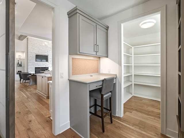 office space with built in desk, light wood-type flooring, and a fireplace