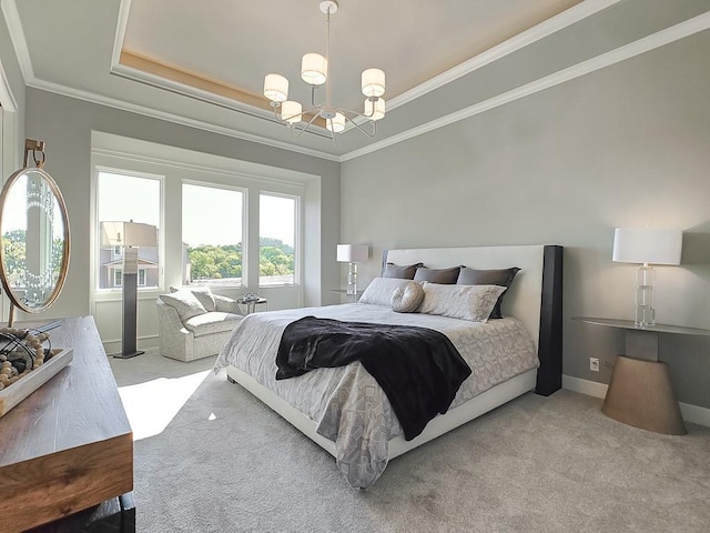 carpeted bedroom with a chandelier, ornamental molding, and a tray ceiling