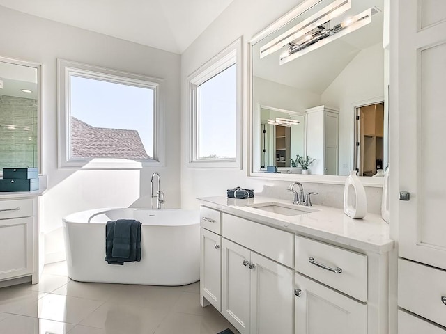 bathroom featuring a tub to relax in, tile patterned floors, vanity, and vaulted ceiling