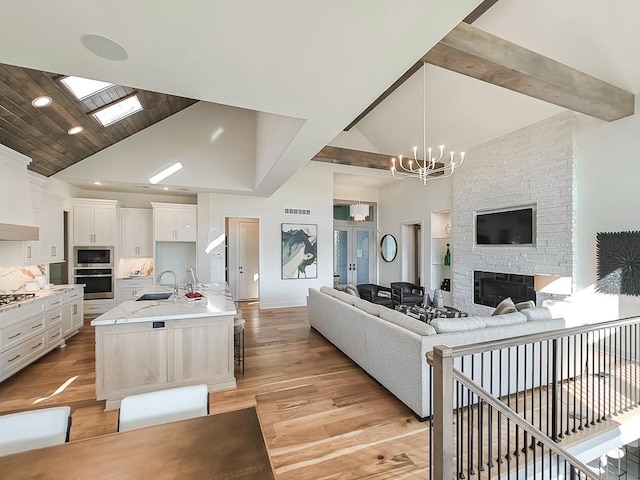 kitchen with sink, white cabinetry, stainless steel appliances, and a kitchen island with sink