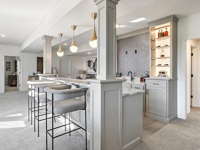 kitchen with pendant lighting, gray cabinets, ornate columns, and light carpet