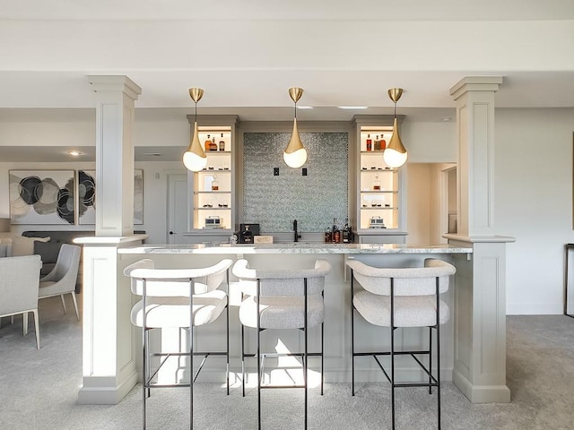 interior space featuring decorative backsplash, ornate columns, and hanging light fixtures