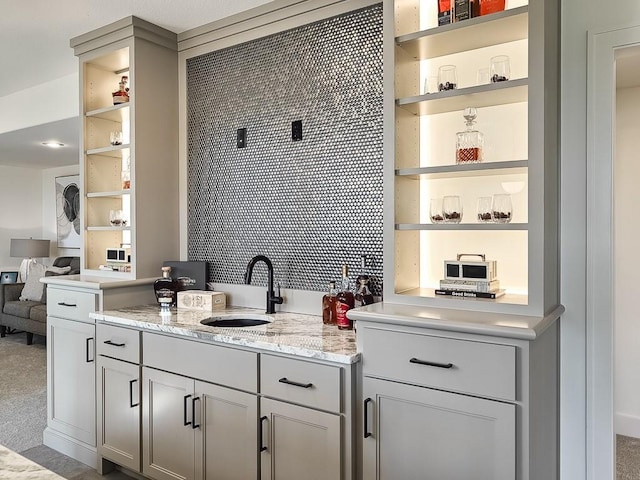 kitchen with built in shelves, light stone countertops, sink, and carpet floors