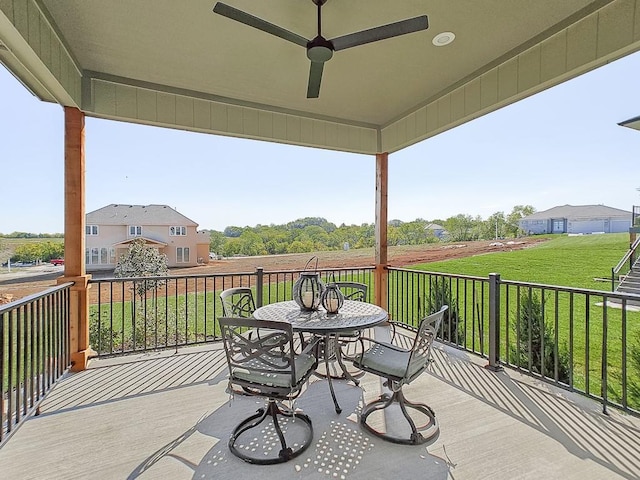 wooden terrace featuring ceiling fan and a lawn