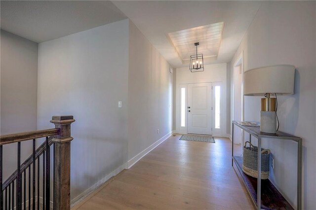foyer with a notable chandelier, baseboards, and wood finished floors