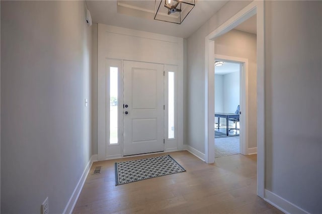 foyer with baseboards, visible vents, and light wood finished floors