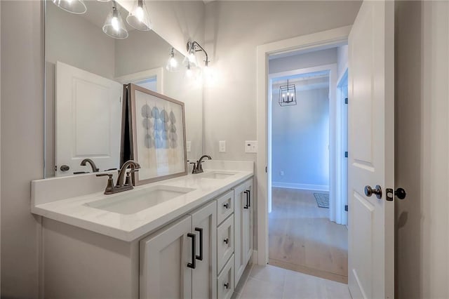 bathroom featuring a sink, baseboards, double vanity, and tile patterned floors