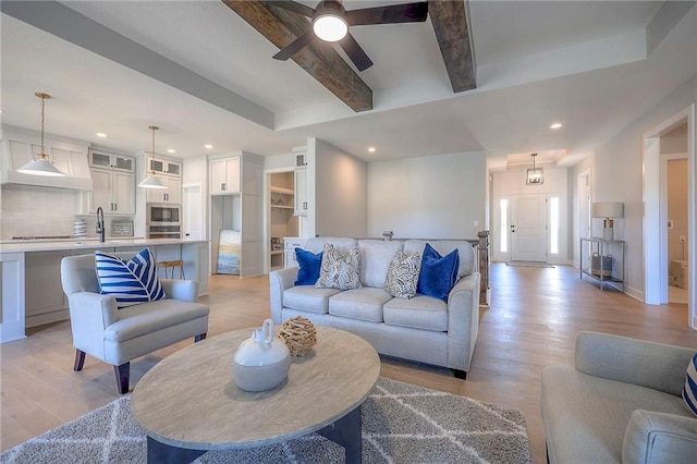 living room featuring baseboards, light wood-style flooring, recessed lighting, ceiling fan, and beamed ceiling