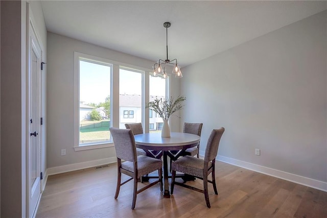dining room featuring visible vents, a notable chandelier, light wood-style floors, and baseboards
