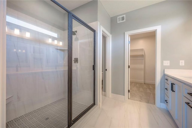 full bathroom with visible vents, a walk in closet, a shower stall, baseboards, and vanity