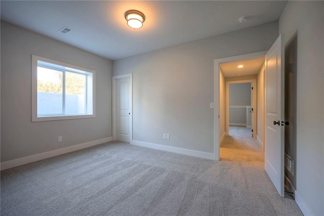 unfurnished bedroom featuring visible vents, light colored carpet, and baseboards