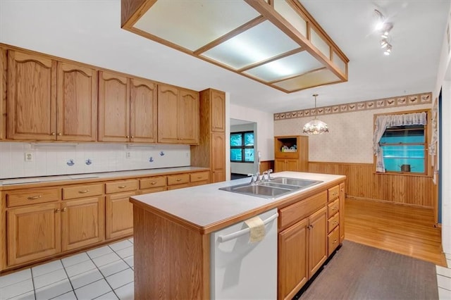 kitchen with dishwasher, light hardwood / wood-style floors, hanging light fixtures, sink, and a center island with sink