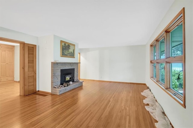 unfurnished living room with a fireplace, light hardwood / wood-style floors, and a wood stove