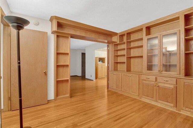 unfurnished living room featuring built in shelves and light wood-type flooring