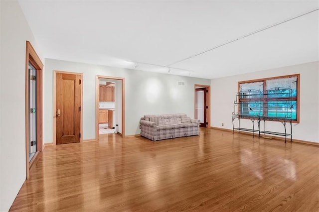 unfurnished living room with light hardwood / wood-style floors and rail lighting