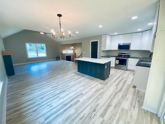 kitchen with light hardwood / wood-style flooring, a chandelier, hanging light fixtures, white cabinets, and stainless steel appliances