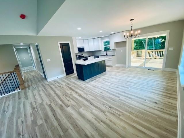 kitchen with a notable chandelier, light hardwood / wood-style floors, white cabinetry, and stove