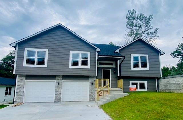 split foyer home with a garage and a front yard