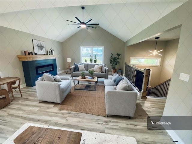 living area with a glass covered fireplace, vaulted ceiling, and ceiling fan