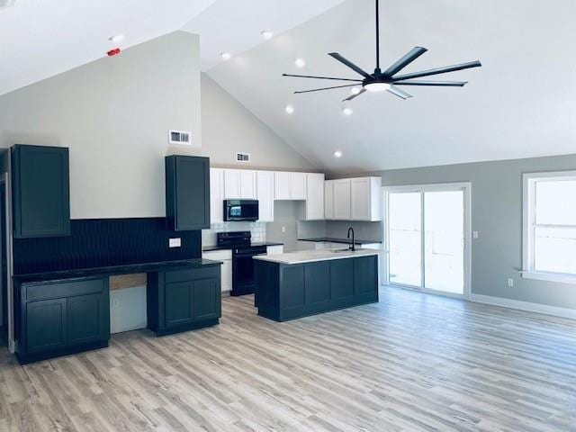 kitchen with a kitchen island with sink, white cabinetry, baseboards, light wood-type flooring, and black appliances