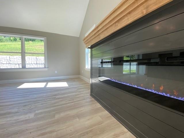 kitchen featuring lofted ceiling, light wood-style flooring, and baseboards