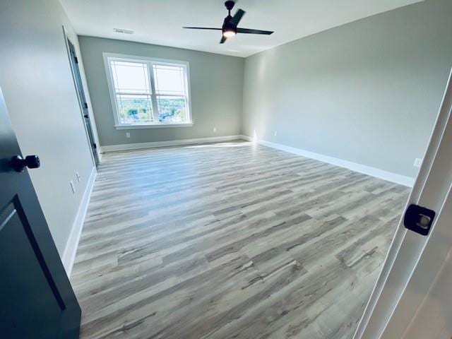 unfurnished bedroom with a ceiling fan, wood finished floors, visible vents, and baseboards