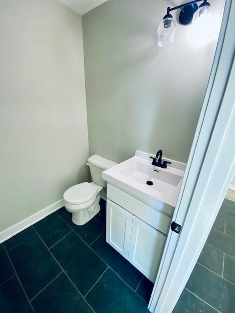 bathroom with toilet, baseboards, vanity, and tile patterned floors