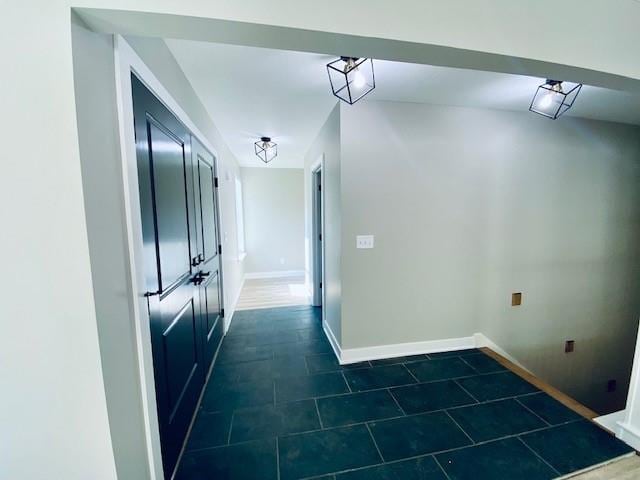 clothes washing area with dark tile patterned floors and baseboards