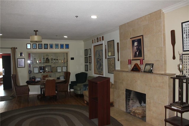 living room with a tiled fireplace, tile walls, a textured ceiling, dark hardwood / wood-style flooring, and ornamental molding