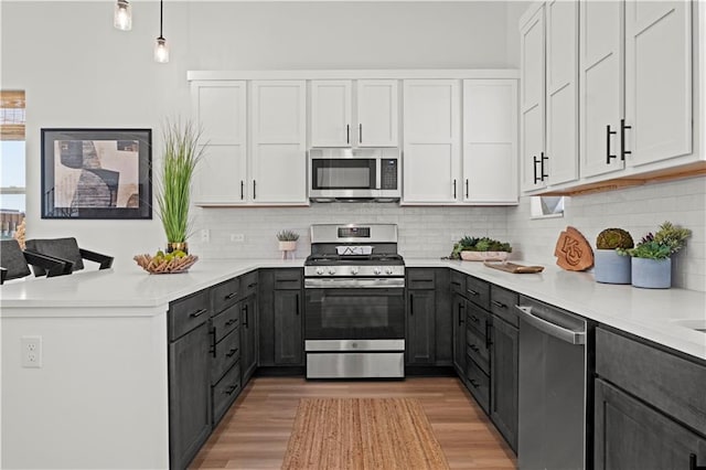 kitchen with white cabinetry, light hardwood / wood-style floors, stainless steel appliances, and decorative light fixtures