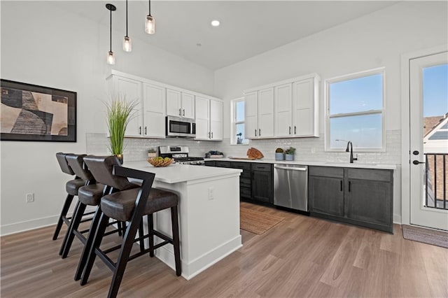 kitchen with a kitchen bar, white cabinets, hanging light fixtures, and stainless steel appliances