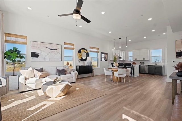 living room featuring ceiling fan, sink, and light wood-type flooring