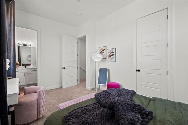 bedroom featuring connected bathroom and light carpet