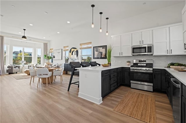 457 SW Longview Blvd, Lees Summit, MO 64081 - kitchen featuring appliances with stainless steel finishes, open floor plan, a peninsula, white cabinetry, and tasteful backsplash