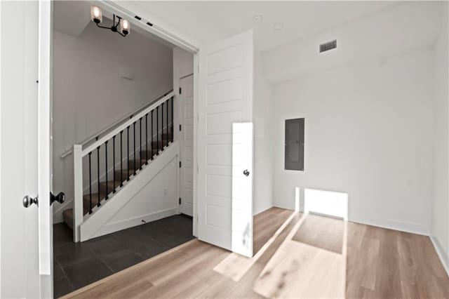 interior space featuring wood-type flooring, electric panel, and an inviting chandelier