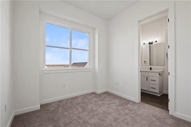 unfurnished bedroom with light carpet, ensuite bathroom, and sink