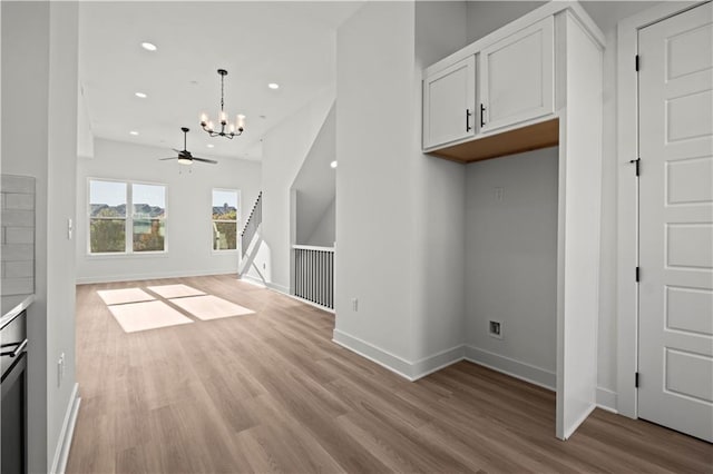 unfurnished living room with ceiling fan with notable chandelier and light wood-type flooring