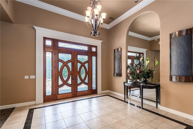 tiled foyer featuring a chandelier, ornamental molding, and a healthy amount of sunlight